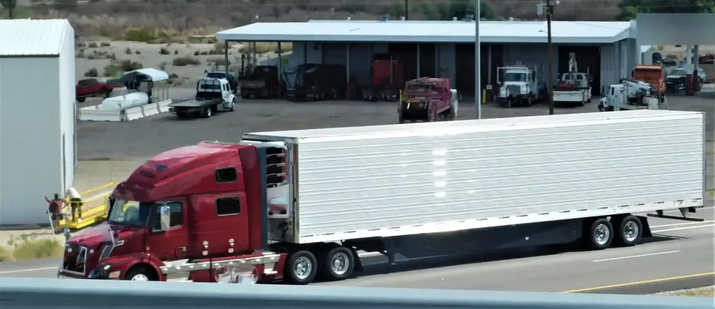 Tracteur routier rouge et semi-remorque réfrigérée dans une cour